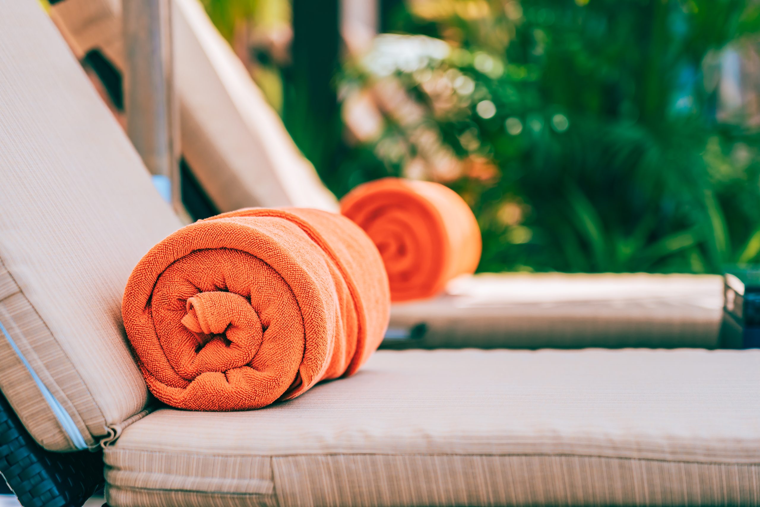 Orange pool towel on deck chair around swimming pool in hotel resort for vacation travel and leisure